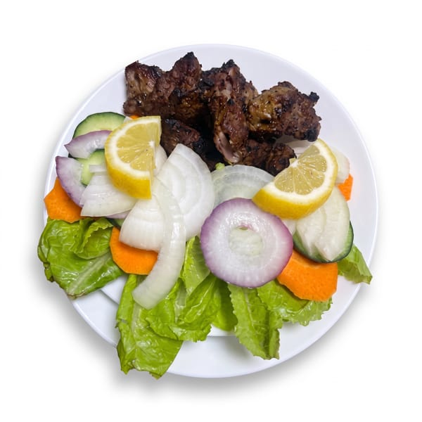 Grilled meat pieces with a side salad of lettuce, carrots, onions, cucumbers, and lemon wedges.